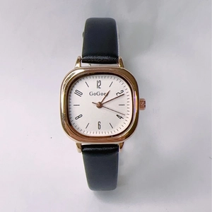 Flat lay of vintage square gold watch with white dial and black leather strap