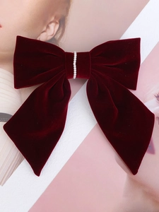 Detail of burgundy velvet hair bow clip with elegant pearls and long ribbon stream