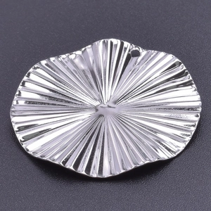 Macro detail of textured silver stainless steel circular charm with radial pattern