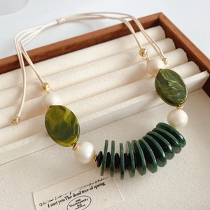 Detail of vintage necklace with green resin beads, pearls, and adjustable cord
