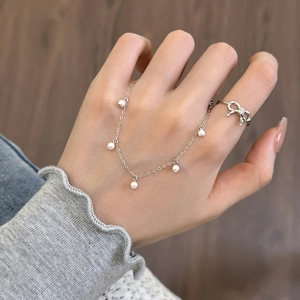Set di gioielli in argento S925 con bracciale di perle e anello con fiocco sulla mano