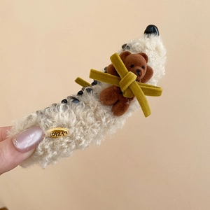 Detailed view of sherpa banana clip with brown teddy bear and green velvet bow detail