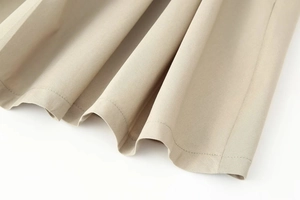 Detail of beige twill fabric showing high-quality stitching and dress hem texture