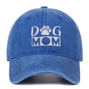 Close-up of DOG MOM white embroidery and vintage washed denim texture on blue baseball cap