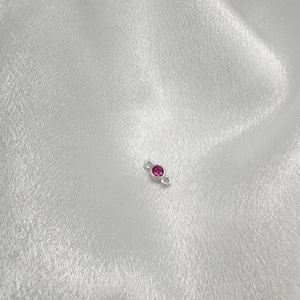 Detail of S925 silver pendant connector with pink gemstone on white satin fabric