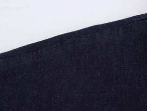 Macro d'une robe midi en jean bleu foncé montrant le sergé et les coutures de précision