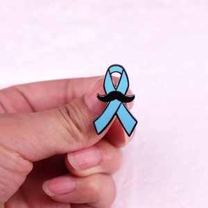 Primo piano dettagliato di una spilla a nastro blu con baffi neri per la salute maschile.