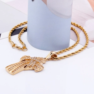 Detail of gold hip hop cross pendant with pave crystals on a twisted rope chain