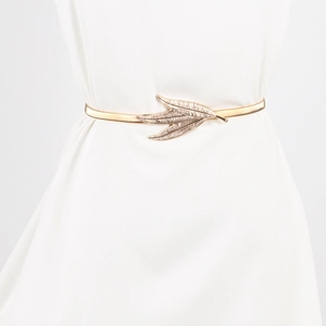 Detail of a golden leaf buckle elastic metal waist chain on a white dress