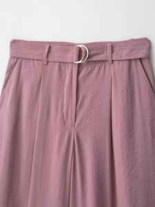 Detail of mauve high-waisted trousers featuring a self-fabric belt with metal D-rings