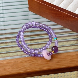 Close-up of double-layer purple amethyst bead bracelet with a pink jade donut charm