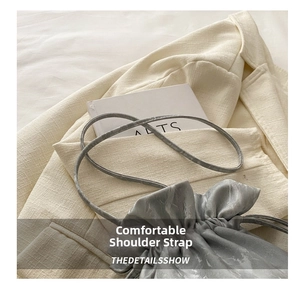 Detailed close-up of comfortable satin shoulder strap on a grey drawstring bucket bag