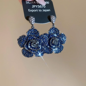 Macro shot of S925 silver blue camellia earrings with pavé-set shimmering cubic zirconia