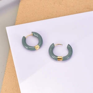 Détail des boucles d'oreilles créoles plaquées or 18K avec émail vert sauge sur papier