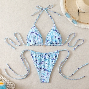 Flat lay of floral bikini set with halter top and side-tie bottoms on a beach mat