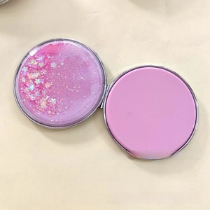 Close-up of pink glitter quicksand folding makeup mirror with sparkling star sequins