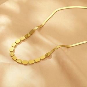 Macro shot of gold geometric square links on a snake chain with LOVE engraving
