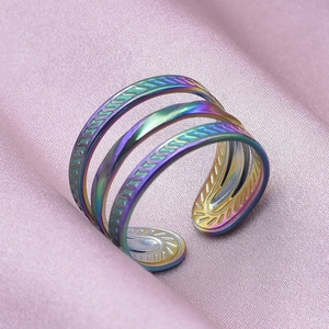 Macro shot of rainbow-colored layered open ring with textured bands on pink silk fabric