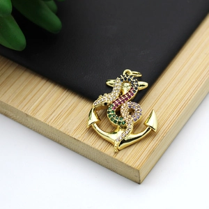 Macro shot of 18K gold plated anchor and snake pendant with colorful zircon stones
