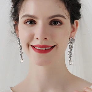 Macro detail of silver long dangle earrings with cascading crystals on bridal dress