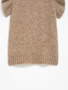 Close-up of soft camel brown knit fabric texture and ribbed hem detail on women's sweater