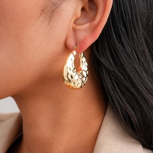 Modern 18K gold-plated teardrop hoop earrings with textured hammered finish on model