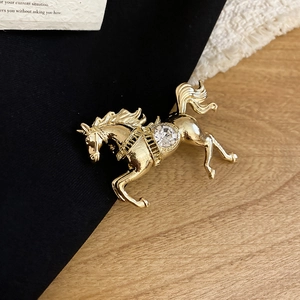 Macro shot of a gold horse brooch featuring a large sparkling gemstone on a dark fabric