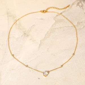 Detail of 18K gold plated necklace with white heart zircon pendant and round accent stones