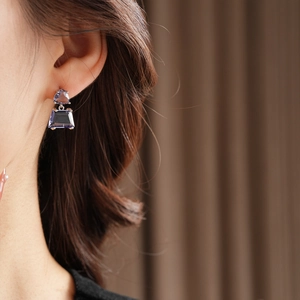 Macro shot of silver earrings with purple heart and trapezoid gemstones on model