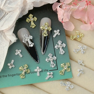 Close-up of gold and silver cross nail charms with rhinestones on display