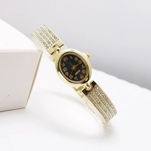 Detail shot of golden rhinestone watch band with elegant oval black dial dial