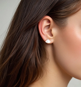Macro detail of silver S925 sterling silver shell earrings showing brushed metal texture