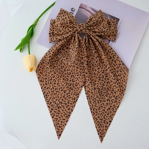 Detail of leopard print oversized bow hair clip with long streamers on a magazine