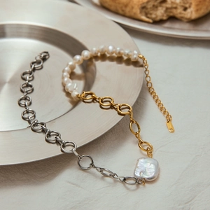 Detail of dual-tone 18k gold and silver necklace with baroque pearl on a metal plate