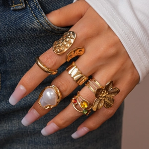 Detail of stacked bohemian gold rings with pearls and rhinestones on denim background