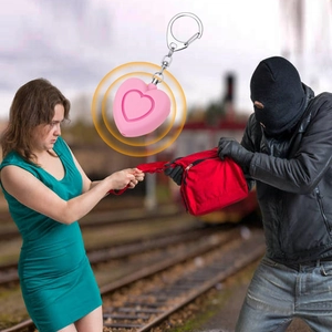 Pink heart-shaped safety alarm with keychain emitting loud sound in emergency scene