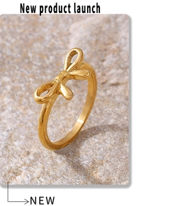 Detailed view of gold bow ring on stone surface with polished 18K PVD finish