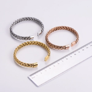 Detailed view of three braided stainless steel cuffs in gold, rose gold and silver colors