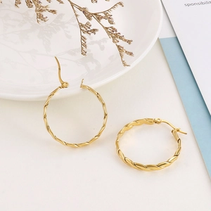 Close-up of gold-plated titanium steel hoop earrings with twisted spiral texture detail