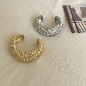 Detailed view of gold and silver ear cuffs with textured embossed metal stripes