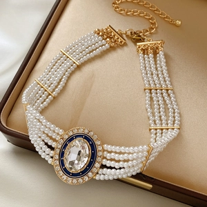 Detail of multi-layer pearl choker with blue enamel oval gemstone in a jewelry box