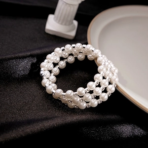 Detailed close-up of multilayered white pearl bracelet with sparkling silver rhinestones