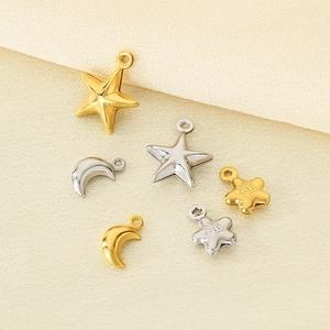 Macro detail of 18K gold and silver star and moon pendants with Fu character engraving