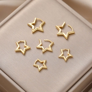 Three pairs of golden star-shaped stud earrings displayed on a beige jewelry box
