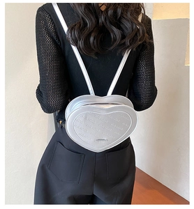 Silver heart-shaped backpack with letter embossing and slim straps on a model