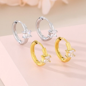 Detailed view of gold and silver hoop earrings with square cubic zirconia stones