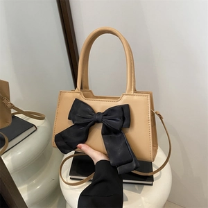 Beige faux leather handbag for women featuring a large black decorative silk bow
