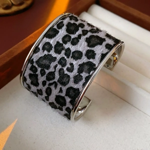 Close-up of wide cuff bracelet featuring black and white leopard print flocking texture