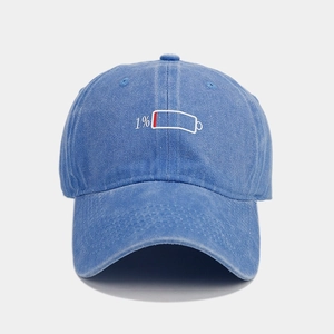 Detailed close-up of 1% low battery embroidery on blue washed cotton baseball cap