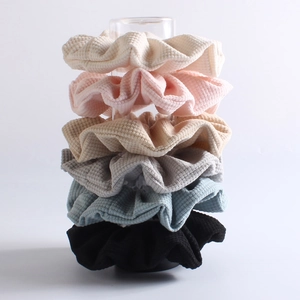 Vertical stack of six textured waffle-knit scrunchies in assorted earthy pastel colors